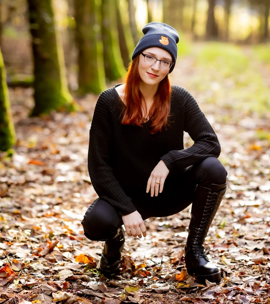 Dekolleté hockt im herbstlichen Wald mit Mütze