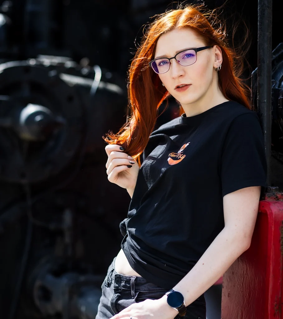 FinaFoxy in schwarzem T-Shirt lehnt an einer Wand