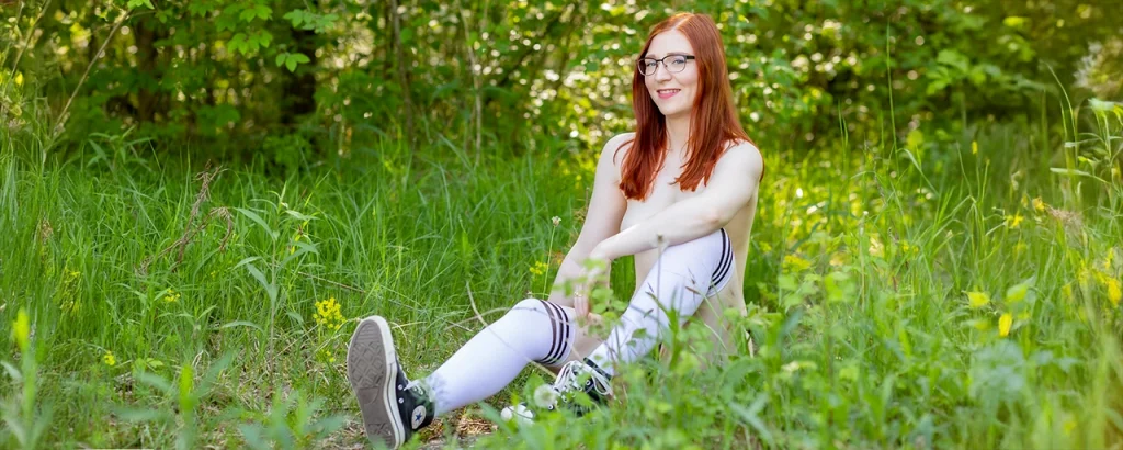 FinaFoxy sitzt auf einer Wiese mit Kniestrümpfen